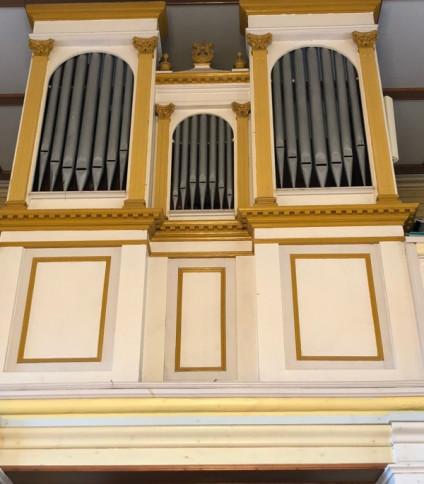 Fasada organów w Solecznikach Małych na Litwie ma trzy sekcje z pionowymi piszczałkami, otoczone białymi i złotymi panelami. Środkowa sekcja jest mniejsza, z dekoracyjnymi elementami na górze.
