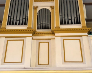 Fasada organów w Solecznikach Małych na Litwie ma trzy sekcje z pionowymi piszczałkami, otoczone białymi i złotymi panelami. Środkowa sekcja jest mniejsza, z dekoracyjnymi elementami na górze.