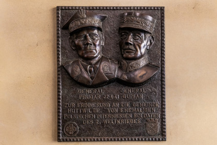 Brązowa tablica z reliefowymi portretami generałów Bronisława Prugara-Ketlinga i Henriego Guisana w Huttwil. Napis w języku niemieckim upamiętnia ich spotkanie 22 kwietnia 1941 roku. Zawiera herby dywizji i kantonu.