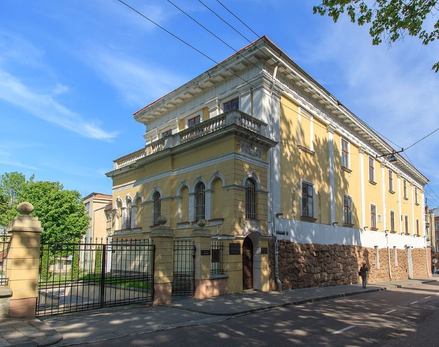 The Baworowski Library building in Lviv, a two-story neoclassical structure with pilasters and a balustrade, located at the corner of a street with a gated entrance.