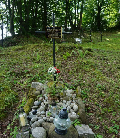 Grób Antoniego Sidełko, polskiego strażnika granicznego, na starym cmentarzu w Mniszku. Grób oznaczony metalowym krzyżem z tabliczką, otoczony kamieniami i zniczami.