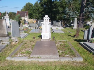 Grób rodziny Marków z kamiennym pomnikiem z inskrypcjami. Pomnik ma dwustopniową podstawę z brakującym krzyżem. Grób otoczony innymi nagrobkami na cmentarzu.