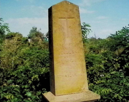 Nagrobek rodzin Mikulskich i Tomaszkiewiczów z obeliskiem na dwustopniowej podstawie. Obelisk z rytym krzyżem i inskrypcją, otoczony zielenią.