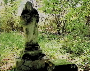 Zniszczona figura Chrystusa na dwustopniowym cokole w trawiastym, zalesionym terenie. Postać bosa, w przepasanej szacie i płaszczu, z dłońmi na piersi. Cokół przypomina skały.