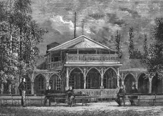 Rycina przedstawiająca zakład wód mineralnych w Druskienikach, 1877. Budynek ma dwupiętrową strukturę z łukami i balkonami. Kilka osób siedzi na ławkach przed budynkiem, otoczonym drzewami.