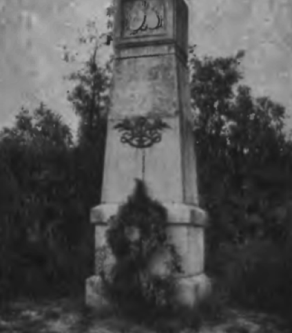 Pomnik generała Bosaka w Burgundii, niedaleko Dijon. Kamienny obelisk z płaskorzeźbami herbów Polski, Litwy i Rusi, otoczony emblematami wojennymi. W tle widoczne drzewa.