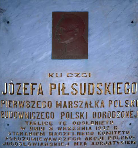 Fotografia przedstawiająca A copy of the painting of Our Lady of the Dawn Gate and a plaque dedicated to Jozef Pilsudski at the Adriatic Sea