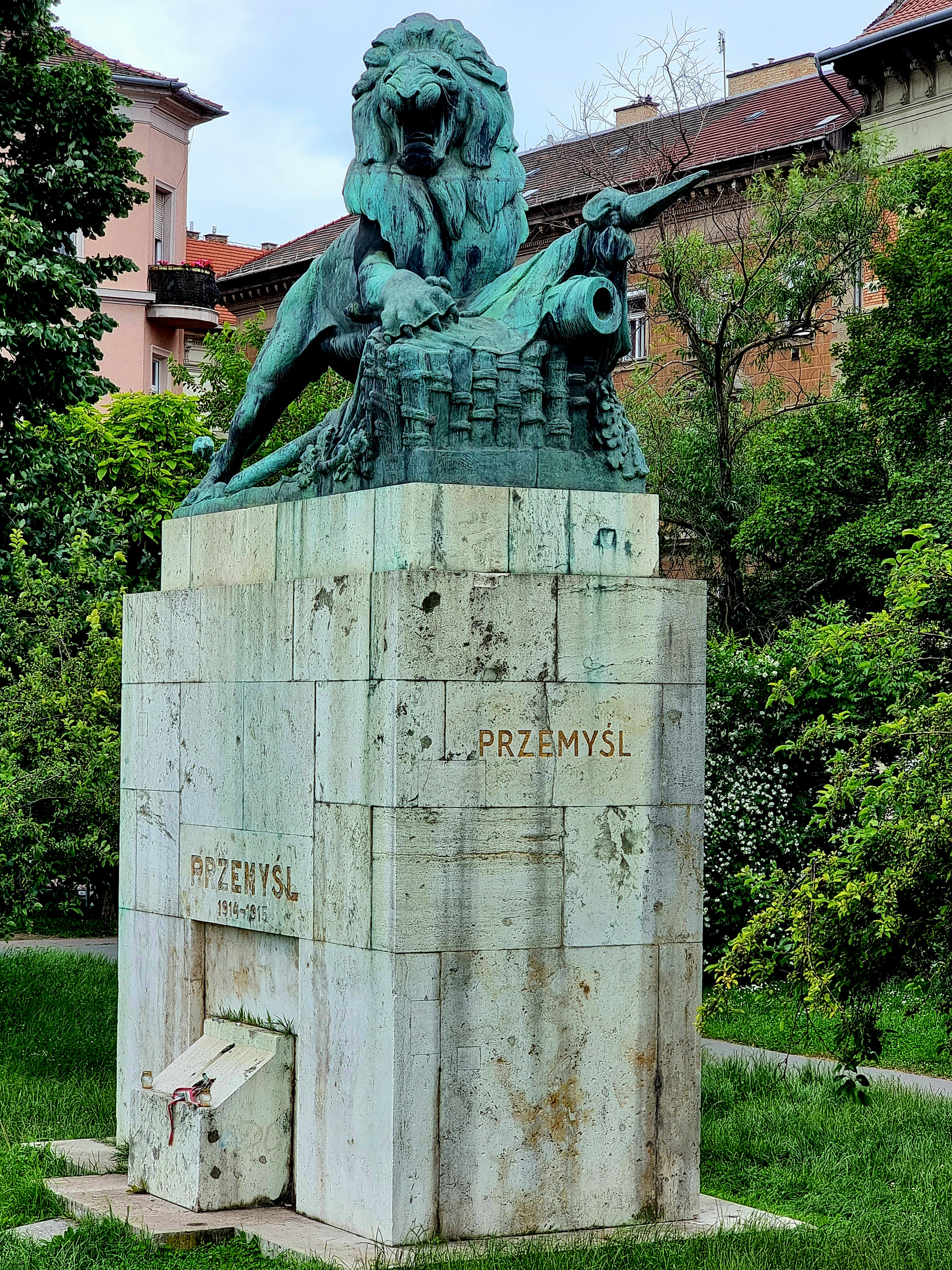 Monument des défenseurs de la forteresse de Przemyśl à Budapest. Un lion en bronze se tient sur un haut piédestal en pierre, avec ses pattes avant sur un canon et un drapeau. Le piédestal est inscrit 'PRZEMYŚL 1914-1915'.