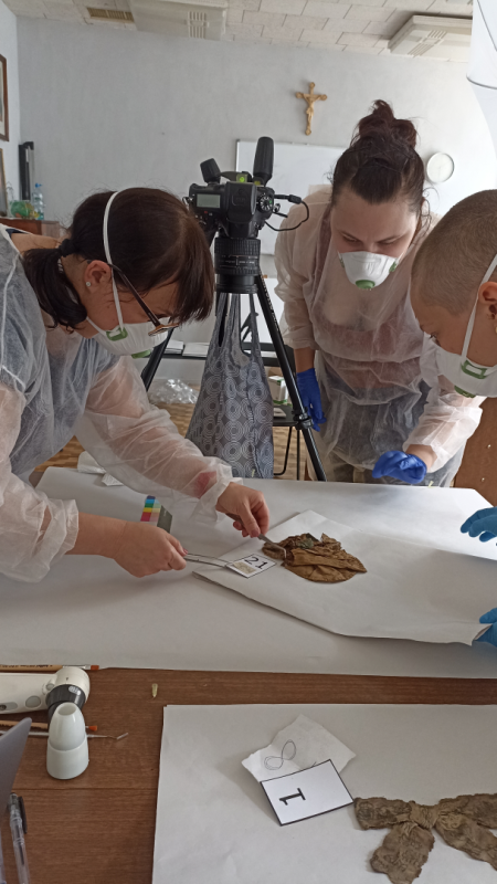 Photo montrant Documentation work and preliminary conservation research on a set of garments and textile fragments from burials in the crypts of the Church of the Holy Spirit in Vilnius (Lithuania)