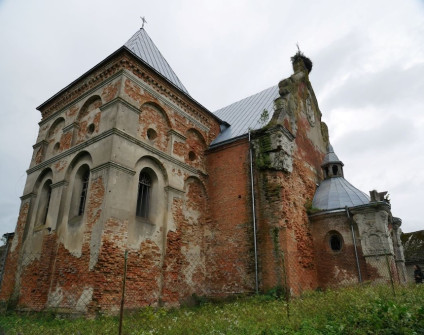 Widok zewnętrzny kościoła św. Michała Archanioła w Starej Soli, Ukraina, z widocznymi uszkodzeniami murów z cegły i tynku oraz metalowym dachem. Detale architektoniczne to łukowe okna i mała kopuła.