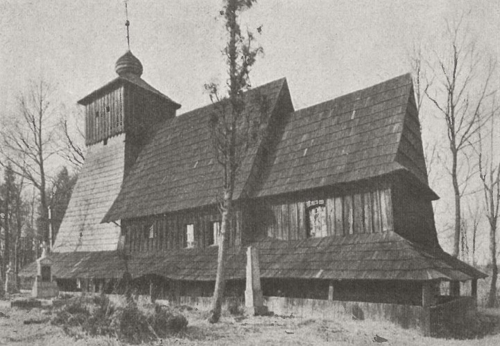 Historic black and white photograph of the wooden Corpus Christi Church in Guty, featuring a Gothic-Renaissance style with a steep roof and a bell tower, surrounded by bare trees.