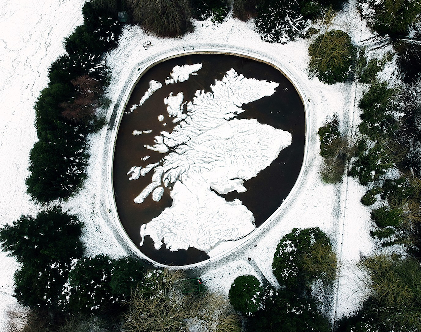 Aerial view of the Great Polish Map of Scotland at Barony Castle, Eddleston. The large 3D relief map, surrounded by snow-covered trees, depicts Scotland in concrete and stone.
