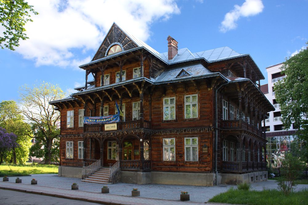 Вілла "Гоплана" в Трускавці, Україна, дерев'яна будівля з елементами закопанського стилю, має крутий дах і декоративні балкони. Фасад прикрашає складна різьба по дереву. Над входом вивіска з написом "Музей".