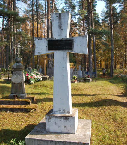 Żelbetowy krzyż na cmentarzu katolickim w Putramiszkach na Łotwie, oznaczający zbiorową mogiłę polskich żołnierzy z lat 1919-1920. Na krzyżu czarna tabliczka z napisami po polsku i łotewsku.