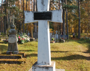 Żelbetowy krzyż na cmentarzu katolickim w Putramiszkach na Łotwie, oznaczający zbiorową mogiłę polskich żołnierzy z lat 1919-1920. Na krzyżu czarna tabliczka z napisami po polsku i łotewsku.