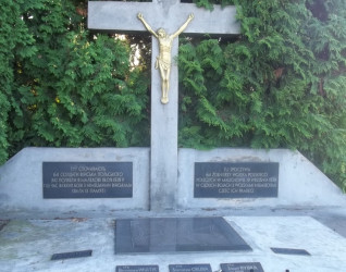 Kamienny krzyż z złotą figurą Chrystusa, otoczony zielenią. Poniżej tablice upamiętniające 64 polskich żołnierzy poległych w Malechowie 19 września 1939 r. Na kamiennej podstawie stoją znicze.