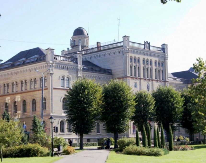 The historic building of the University of Latvia in Riga, formerly Riga Polytechnic, in a classical architectural style, surrounded by trees and a green park.