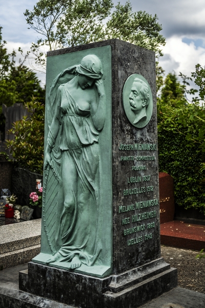 Gravestone of Józef Wieniawski at Ixelles Cemetery in Brussels. The monument features a bronze bas-relief of Muse Euterpe and a medallion with Wieniawski's portrait. Inscription details his life and his wife Melanie.