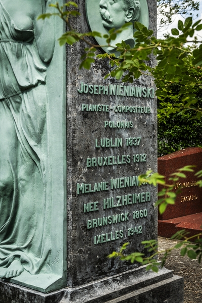 Gravestone of Józef Wieniawski at Ixelles Cemetery in Brussels. The stone features a relief of a woman and inscriptions in French detailing Wieniawski's life and his wife Melanie's details.