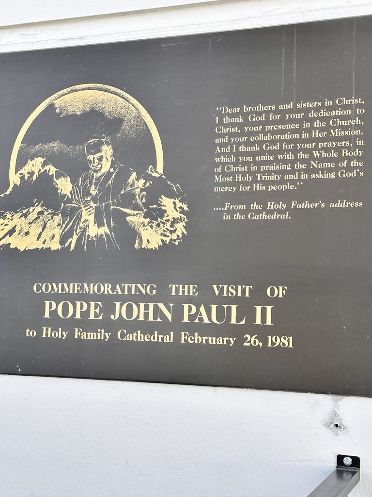 Plaque commémorant la visite du Pape Jean-Paul II à la Cathédrale de la Sainte Famille le 26 février 1981. Présente une image du Pape et une citation de son discours à la Cathédrale.