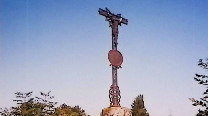 Żelazny krzyż z krucyfiksem na cylindrycznej podstawie, z owalną tabliczką i arkadowymi płycinami o ostrołukowym zwieńczeniu. Cokół ma prostokątną płycinę o ściętych narożach.