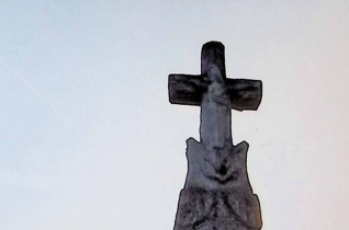 Nagrobek z krzyżem stylizowanym na pień drzewa, z postacią Chrystusa na przecięciu ramion. Poniżej wieniec z liści. Cokół przypomina stos kamieni z inskrypcją na zwoju.