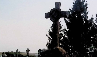 Grób oznaczony krzyżem stylizowanym na pień drzewa na dwustopniowym cokole przypominającym skały, z reliefem korony cierniowej na przecięciu. Rustykalna podstawa z inskrypcją na tablicy w formie zwoju.