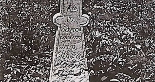 Kamienny krzyż z treflowymi zakończeniami na schodkowej podstawie. Krzyż grecki na pionowej belce. U góry inskrypcja, poniżej mały krzyżyk, następnie kolejna inskrypcja.