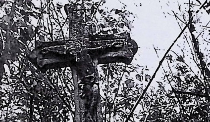 Nagrobek Ludwika Wierzbickiego z krzyżem o stylizowanym wzorze trójliścia i figurą Chrystusa z żłobkowaną aureolą i titulusem. Otoczony roślinnością.