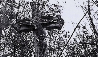 Nagrobek Ludwika Wierzbickiego z krzyżem o stylizowanym wzorze trójliścia i figurą Chrystusa z żłobkowaną aureolą i titulusem. Otoczony roślinnością.