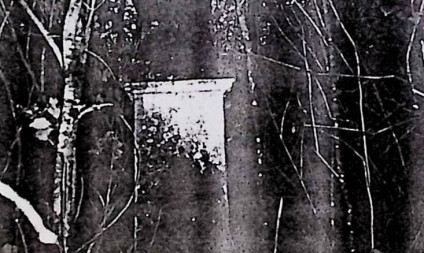 Żeliwny krzyż na kamiennej podstawie z titulusem INRI. W połowie ramienia płytka z kartuszem herbowym i ornamentem roślinnym. U podstawy scena Opłakiwania. Kamienny cokół z prostokątną ramą i rytą inskrypcją.