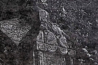 Kamienny cokół z krzyżem na szczycie, otoczony kamieniami. Na wszystkich bokach cokołu płyciny z inskrypcjami.