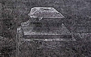 Kamienny cokół z profilowaną podstawą podtrzymującą krzyż. Frontowa inskrypcja otoczona rytą ramą.