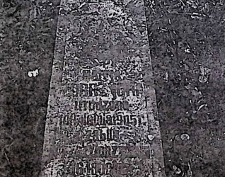 Nagrobek Marii Żóbrzyckiej w kształcie obelisku z wyrytą inskrypcją ujętą w ramę z przodu. Tło inskrypcji ma wcięte naroża.