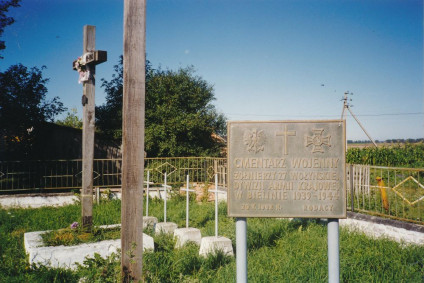 Drewniany krzyż i tablica pamiątkowa na cmentarzu 27 Wołyńskiej Dywizji Piechoty Armii Krajowej w Bielinie. Na tablicy napis: 'Cmentarz wojenny / żołnierzy 27 Wołyńskiej / Dywizji Armii Krajowej / w Bielinie 1939-1944 / 20 X 1992 r. Rodacy'.