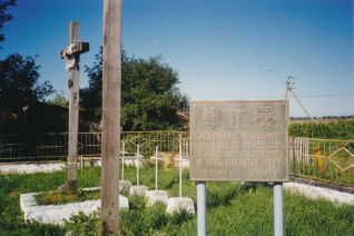 Drewniany krzyż i tablica pamiątkowa na cmentarzu 27 Wołyńskiej Dywizji Piechoty Armii Krajowej w Bielinie. Na tablicy napis: 'Cmentarz wojenny / żołnierzy 27 Wołyńskiej / Dywizji Armii Krajowej / w Bielinie 1939-1944 / 20 X 1992 r. Rodacy'.
