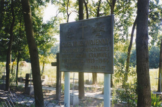 Cmentarz leśny 27. Wołyńskiej Dywizji Piechoty AK w Bielinie. Widoczna tablica z inskrypcjami i krzyżami wśród drzew.