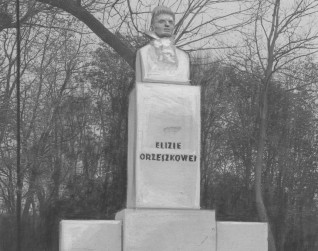 Pomnik Elizy Orzeszkowej w Grodnie, z popiersiem na wysokim prostokątnym postumencie z napisem 'ELIZIE ORZESZKOWEJ'. W tle widoczne drzewa.