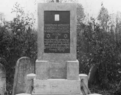 Pomnik w Bohorodczanach upamiętniający nieznanych bohaterów walk o niepodległość Polski, z inskrypcjami w języku polskim i jidysz. W tle widoczne macewy.