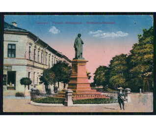 Historyczna pocztówka z pomnikiem Adama Mickiewicza w Tarnopolu, przedstawiająca statuę na wysokim cokole otoczoną drzewami i budynkami.
