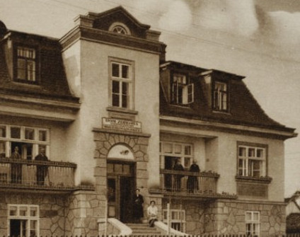 Archiwalne zdjęcie Domu zdrowia dla pracowników Ministerstwa Komunikacji w Truskawcu, 1931. Budynek z centralnym wejściem, kamienną fasadą i balkonami z ludźmi.
