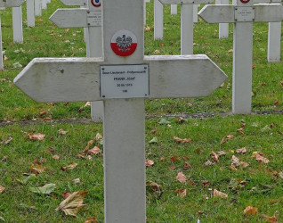 Biały krzyż z emblematem Polski i napisem 'Sous-Lieutenant - Podporucznik Frank Józef 20 06 1919 138' na Cmentarzu Zachodnim. Dwie małe polskie flagi z przodu.
