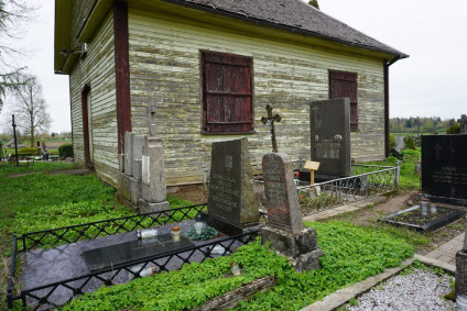Grób Edwarda Pawłowskiego obok kaplicy, z krzyżem i inskrypcją o tragicznej śmierci w 1944 roku w wieku 24 lat. Otoczony innymi grobami i zielenią.