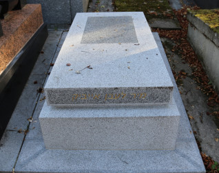 Nagrobek Jakuba Burki z ukośną płaską płytą na schodkowej podstawie. Na froncie inskrypcja hebrajska, na powierzchni tekst francuski. Otoczony opadłymi liśćmi.