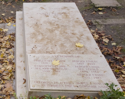 Nagrobek rodzin Bergerów i Pawlotskich z inskrypcjami na skośnej płycie i przymocowanej tablicy. Grób otaczają opadłe liście.