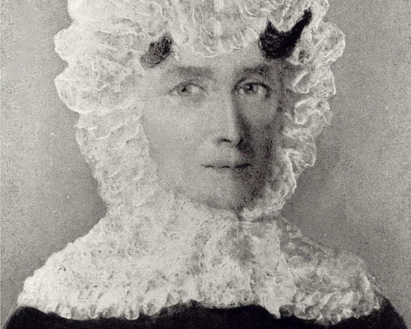 Black and white portrait of a woman wearing a lace cap and dark dress.