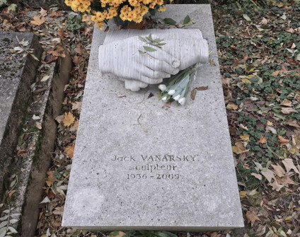 Nagrobek Jacka Vanarskiego z rzeźbą dwóch splecionych rąk na płaskiej płycie. Napis brzmi 'Jack Vanarsky, rzeźbiarz, 1936-2009'. Grób otaczają kwiaty i jesienne liście.