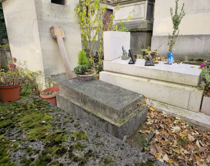 Nagrobek Daniela Zimmermanna z lekko skośną płytą na wysokim cokole. Inskrypcja na lewym boku. Wokół liście jesienne i rośliny w doniczkach.