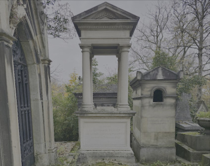Nagrobek Konstancji Ślizień z uskokowym cokołem, kolumnami z bazami i głowicami attyckimi oraz dwuspadowym baldachimem. Widoczne otaczające drzewa i sąsiednie grobowce.