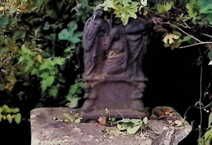 Krzyż żeliwny na dwustopniowym cokole z ramionami w formie roślinnej i wicią akantową. Na przecięciu figura Chrystusa, powyżej titulus, poniżej grupa Opłakiwania z klęczącymi puttami, Matką Boską, św. Janem i św. Marią Magdaleną.